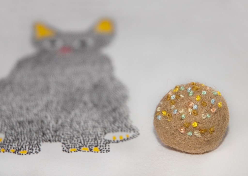 kitten is playing with the sea beads that I am making